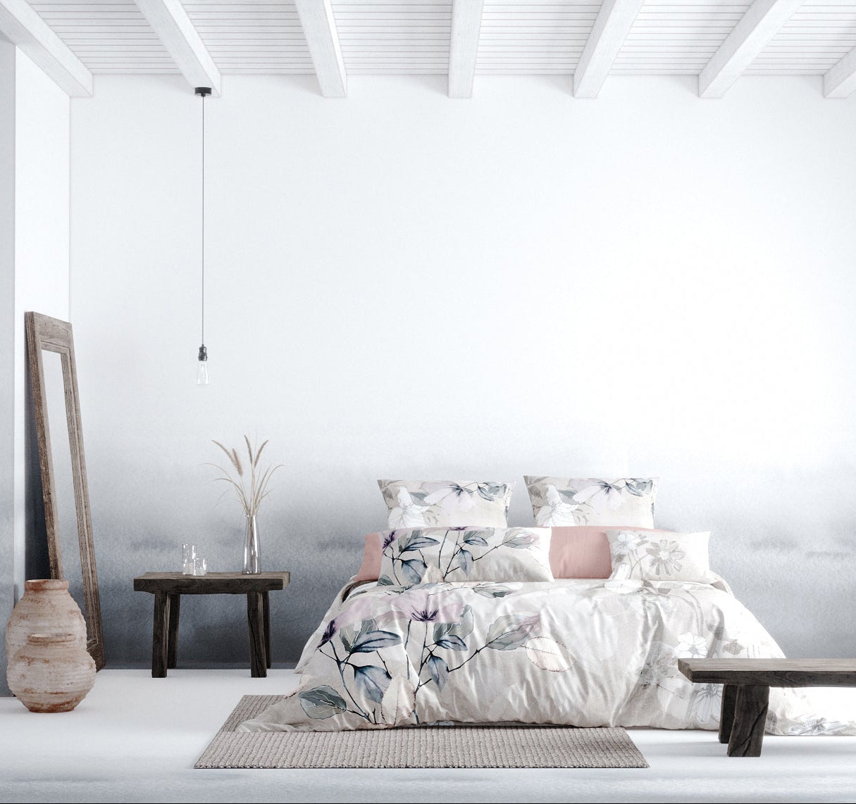 Das Bild zeigt ein minimalistisch eingerichtetes Schlafzimmer mit einem modernen, skandinavischen Stil. Im Mittelpunkt steht ein großes Bett mit einer Bettwäschegarnitur in sanften Naturtönen, die ein florales Muster mit Blüten und Blättern in Beige, Grau und Lila zeigt. Das Bett ist mit mehreren Kissen dekoriert, darunter auch einige mit rosafarbenen Bezügen.